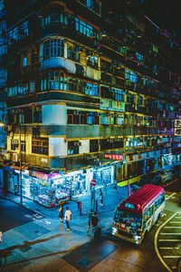 People on street against illuminated buildings in city at night