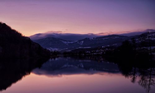 Scenic view of lake and mountains against sky at sunset