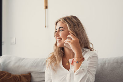 Young woman using mobile phone while sitting on sofa at home