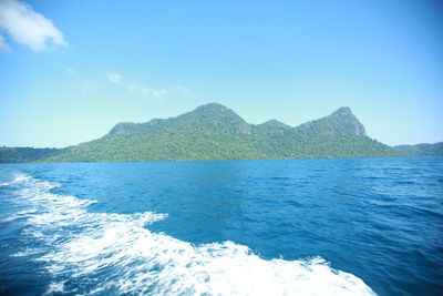 Scenic view of sea and mountains against clear blue sky