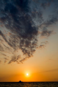 Scenic view of sea against dramatic sky during sunset