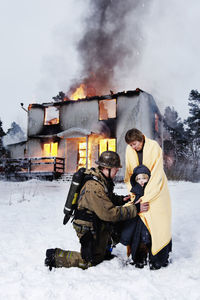 Fireman with rescued woman and girl in front of burning house