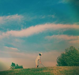 Trees on field against cloudy sky