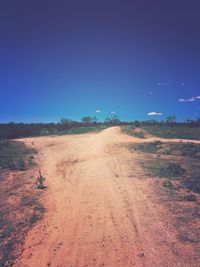 Road amidst field against clear sky