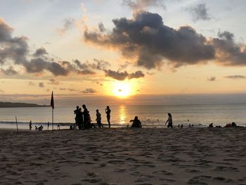 Silhouette people on beach against sky during sunset