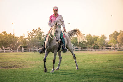 Full length of a person riding horse on field