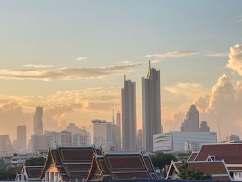 Modern buildings in city against sky during sunset