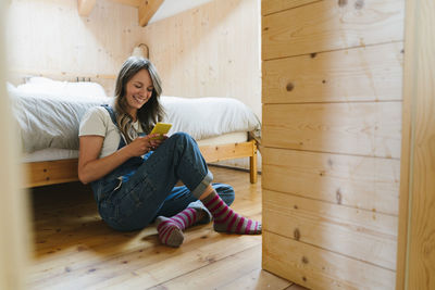 Happy woman using smart phone in bedroom