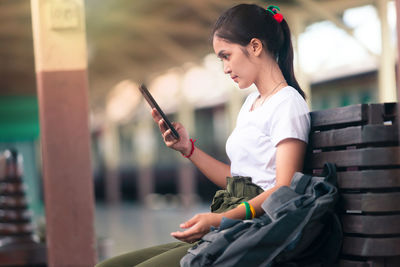 Side view of young woman using mobile phone outdoors