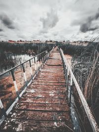 View of wooden bridge against sky during winter