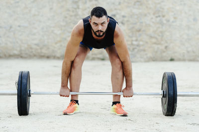 Weightlifter with beard lifting weights in an urban environment.