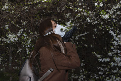Rear view of woman holding umbrella against trees