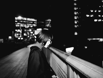 Rear view of woman standing in city at night