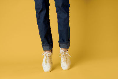 Low section of woman standing against yellow background