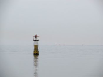 Lighthouse by sea against clear sky