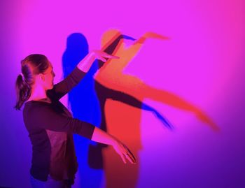 Full length of woman standing against pink wall