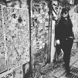 Full length of young woman standing against graffiti wall