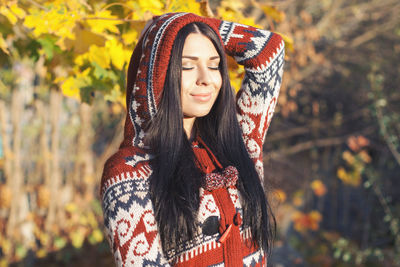 Portrait of smiling young woman standing against plants during autumn