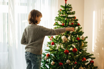 The girl decorates the christmas tree for the holiday. preparing for christmas and new year