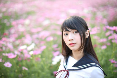 Portrait of beautiful woman standing by pink flower