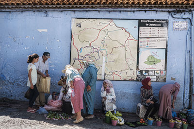 Rear view of people sitting on wall