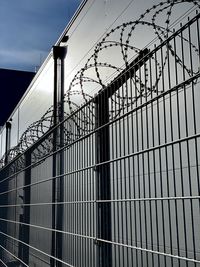 Low angle view of barbed wire fence against sky