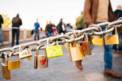 Close-up of padlocks hanging on chain against blurred people