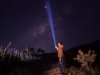 Full length of man standing against illuminated star field against sky at night