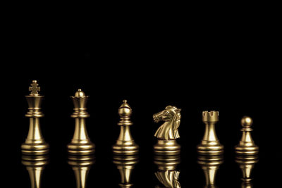 Low angle view of illuminated chess pieces against black background