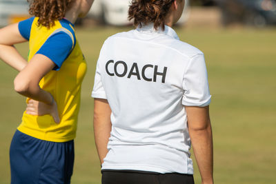 Rear view of friends standing on soccer field