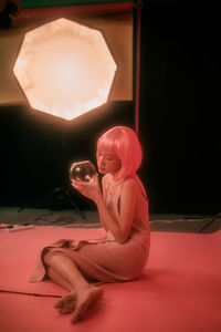 Young woman sitting in illuminated room