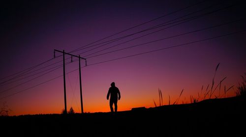 Silhouette man standing on field against sky during sunset