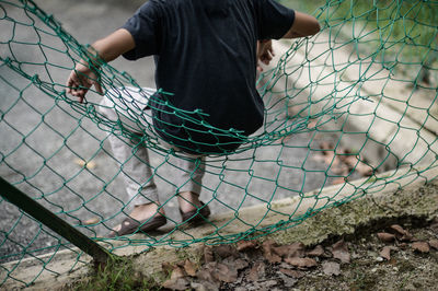 A boy sitting on a broken chainlink fencing