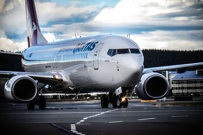 Airplane on airport runway against sky