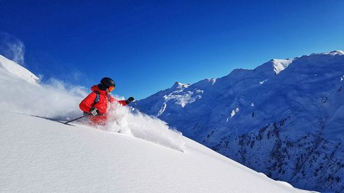 Low angle view of person skiing on snowcapped mountain against sky