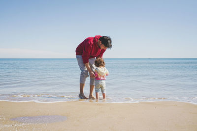 Father and daughter standing at seashore