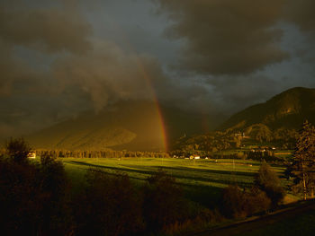 Scenic view of rainbow over land against cloudy sky