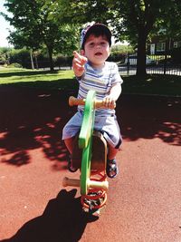 Portrait of cute baby boy sitting on outdoor play equipment