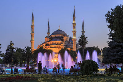 Tourists in front of illuminated sultan ahmed mosque at dusk