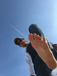 Low angle view of man holding umbrella against blue sky