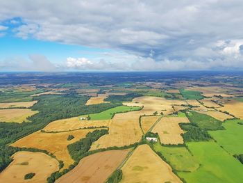 Aerial view of patchwork landscape against cloudy sky