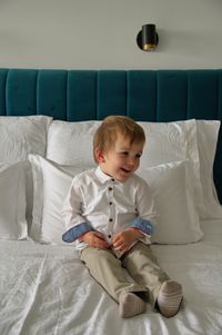 Little boy dressed for celebration sitting on a bed