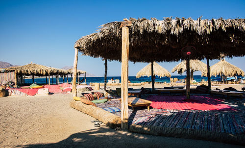 Lounge chairs and parasols on beach against clear sky