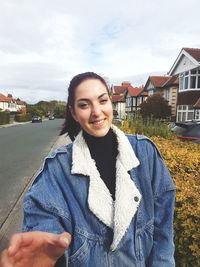 Portrait of smiling young woman standing against building