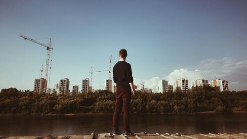 Rear view of man standing by cityscape against sky