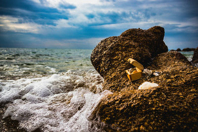 Rocks on shore at beach against sky