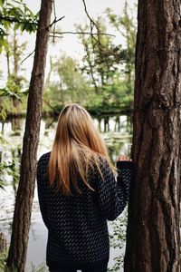 Rear view of woman looking at tree trunk