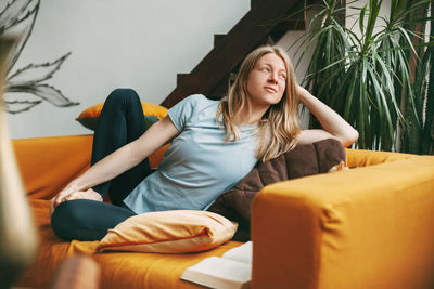 Young woman sitting on sofa at home