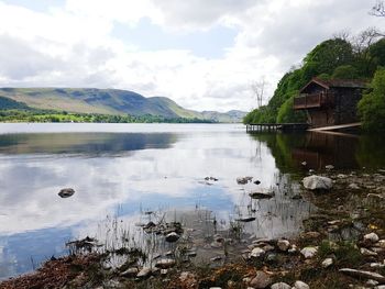 Scenic view of lake by mountains against cloudy sky