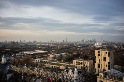 High angle view of city buildings against cloudy sky